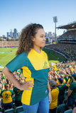 Woman wearing official Wallabies green and gold jersey standing against wooden wall